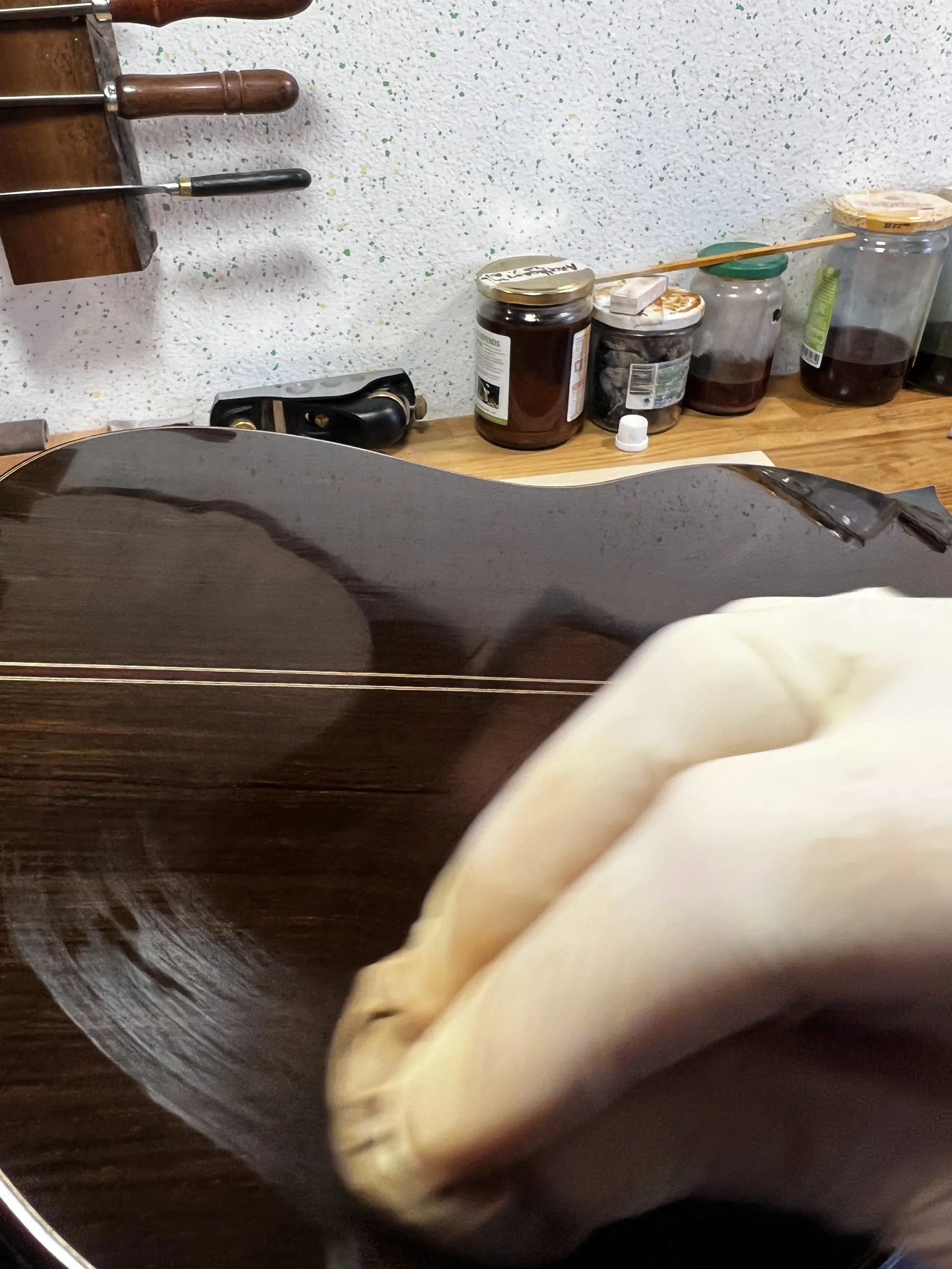 The comet tail following the pad's movement — alcohol evaporating, a sign the varnish is flowing and setting correctly