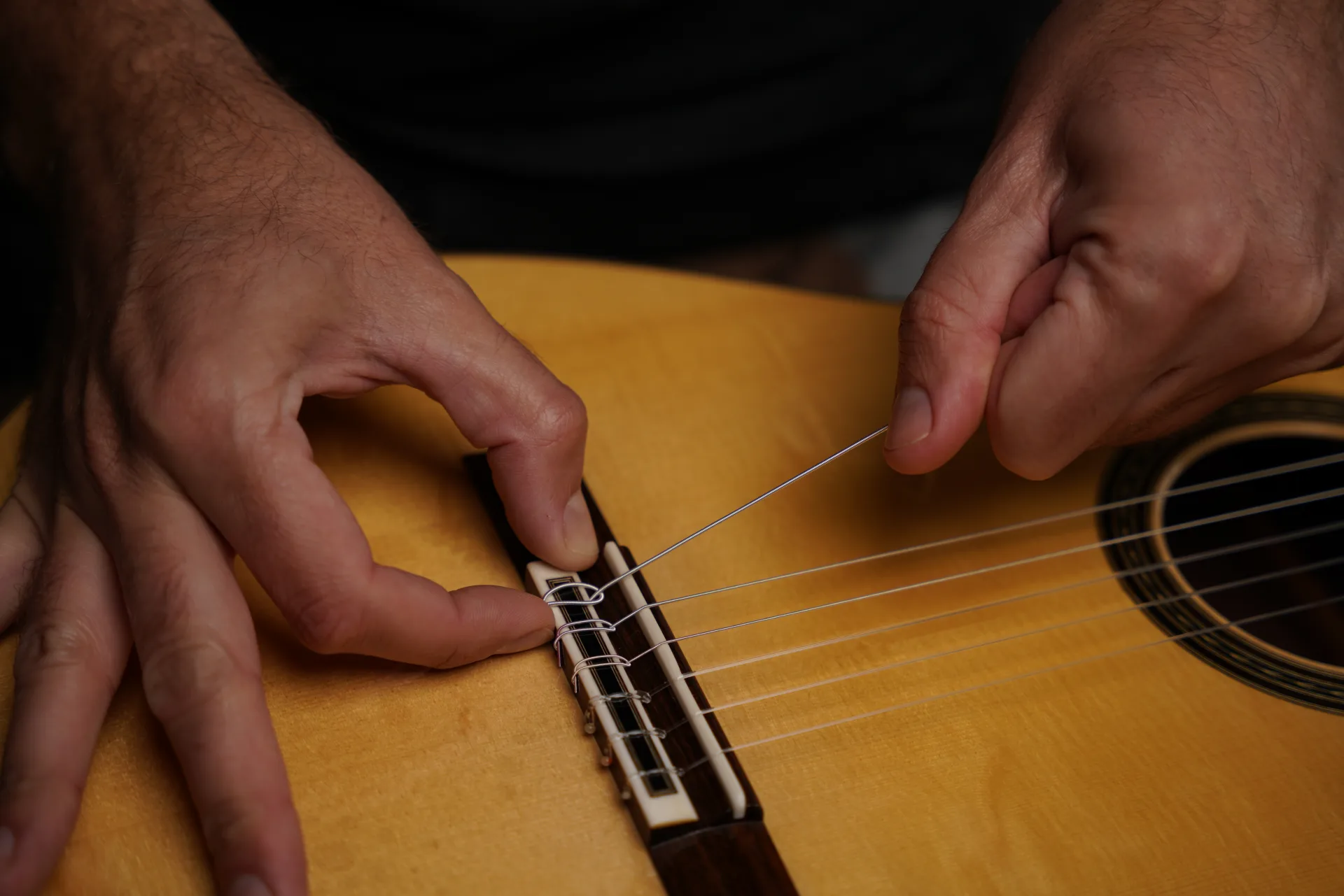 Hold the loose end firmly in place against the bridge and tighten the knot