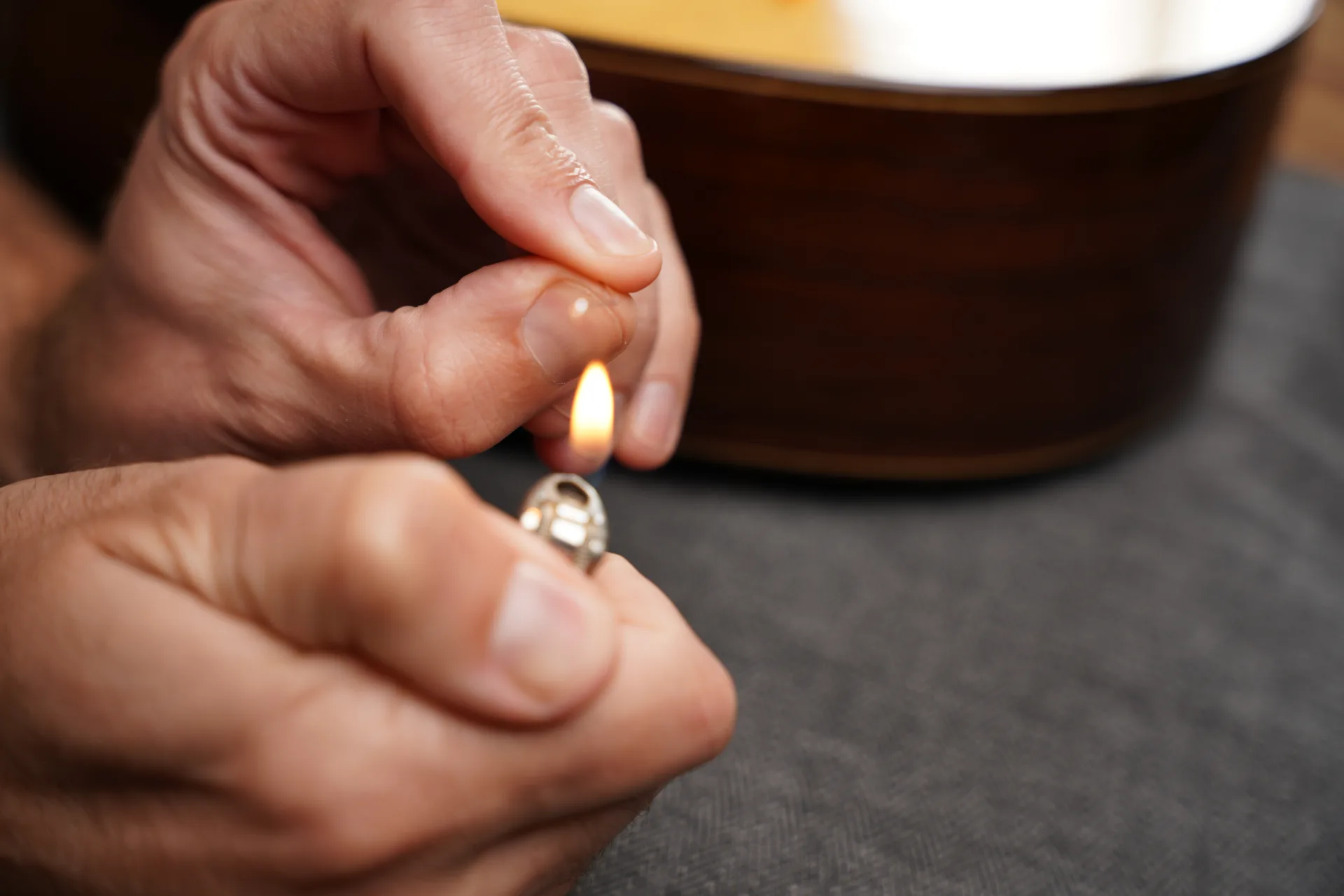 Using a lighter to create a small ball at the end of a treble string — do this away from the instrument