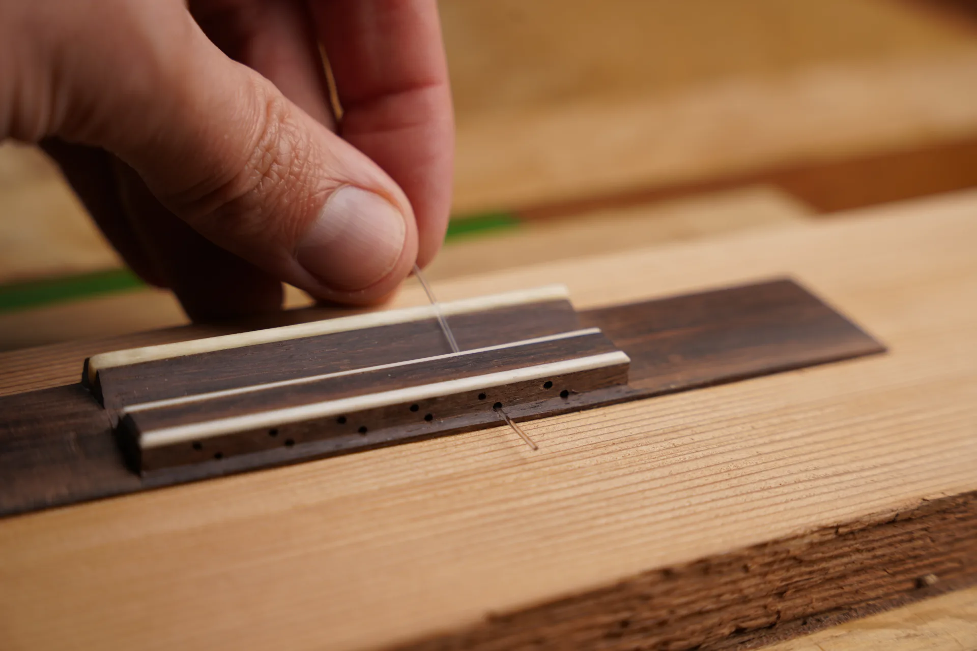 Pass the treble string through the lower hole of the 12-hole bridge