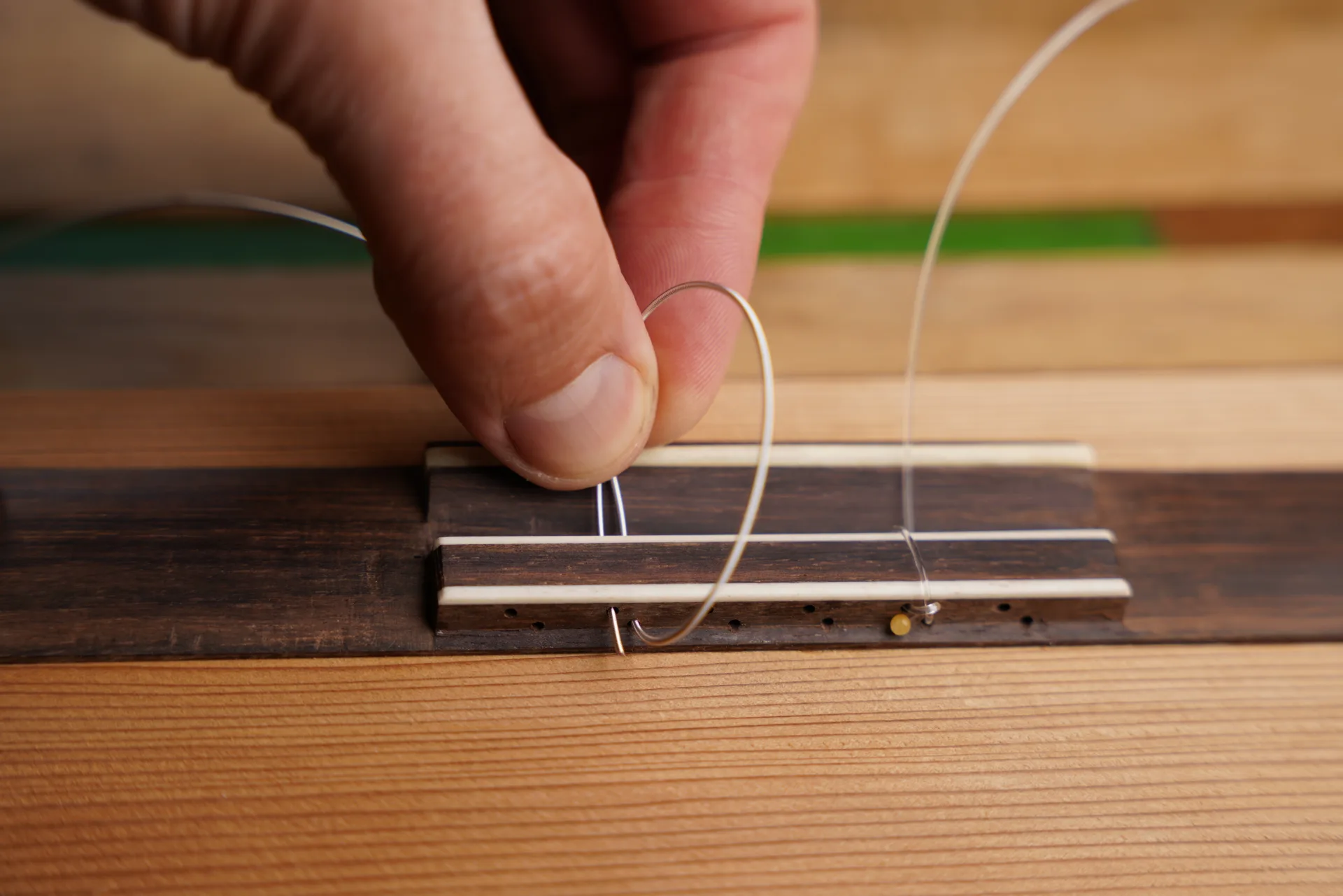 Start the bass string the same way — pass through the lower hole and form a loop