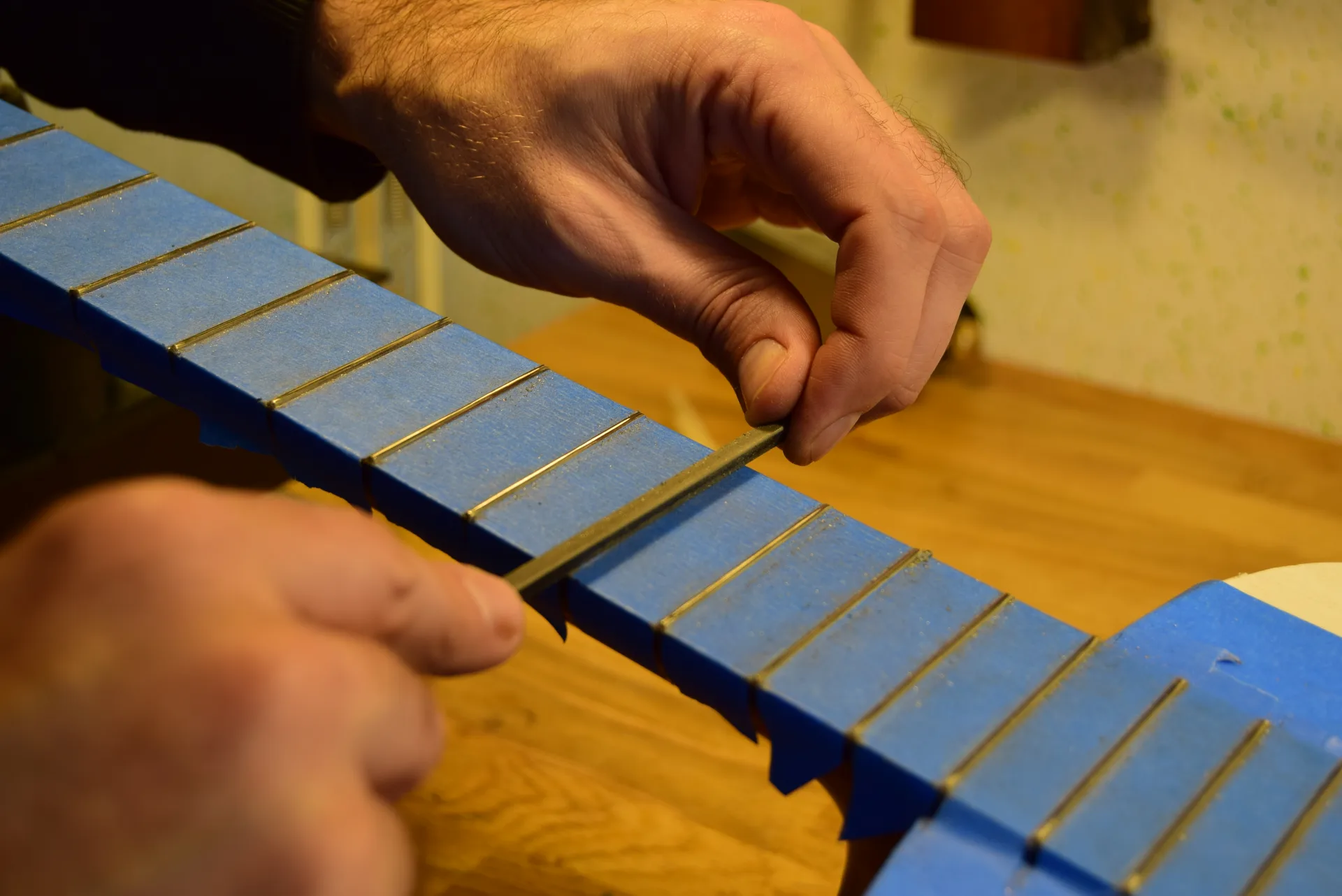 Recreating the crown of each fret with a fret-crowning file — critical for accurate intonation